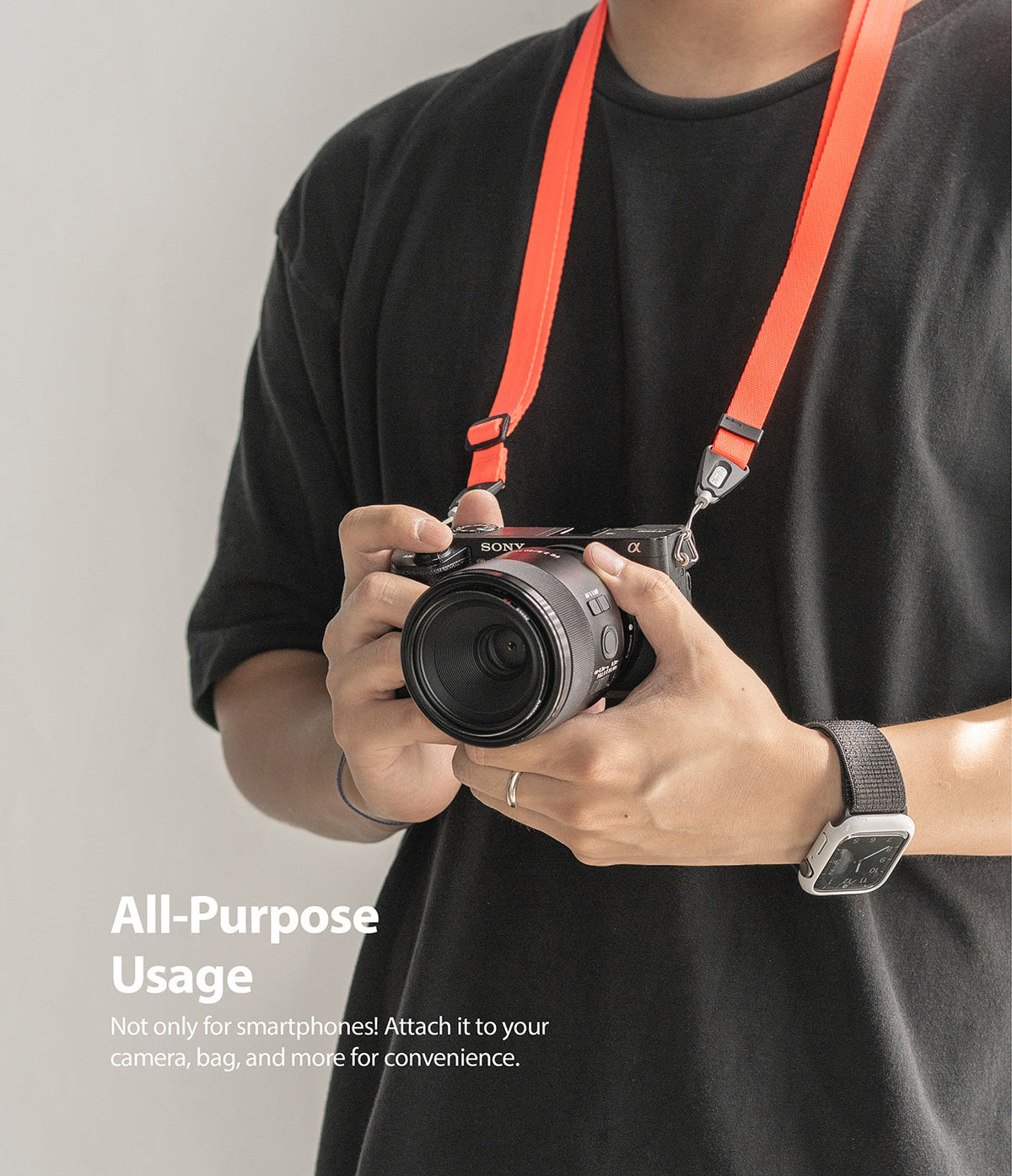 Shoulder Strap | Black / Neon Orange - Person wearing a neon orange shoulder strap attached to a black Sony camera.