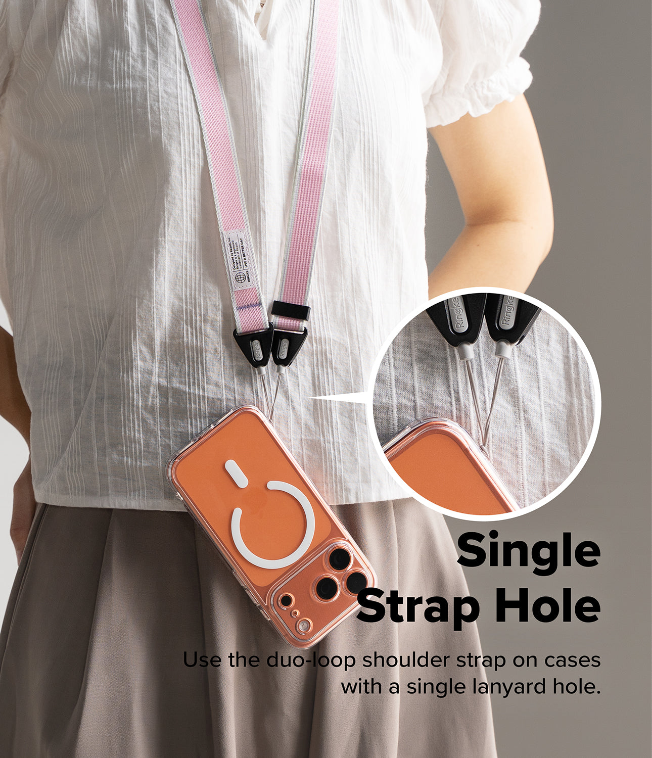 Design Shoulder Strap - Person wearing a pink and white phone strap attached to a single lanyard hole on an orange phone case.