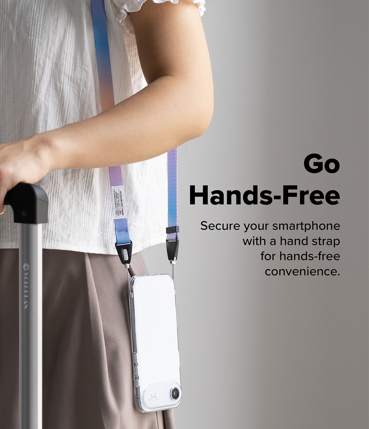 Shoulder Slim Strap - A person wearing a colorful gradient phone strap attached to a clear smartphone case while holding luggage.