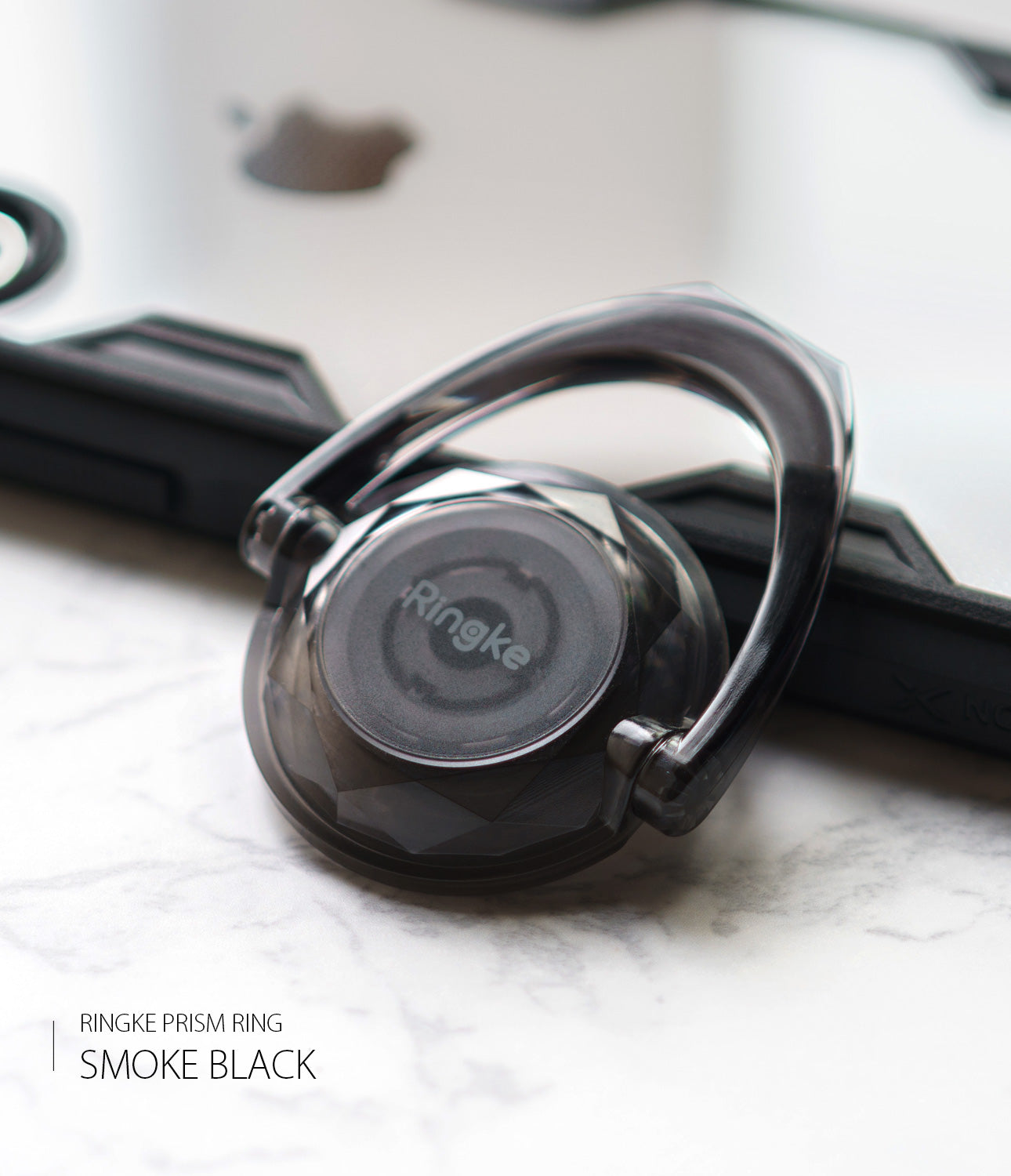 Prism Ring - A translucent smoke black Ringke phone ring holder with a faceted, gem-like design on a marble surface.