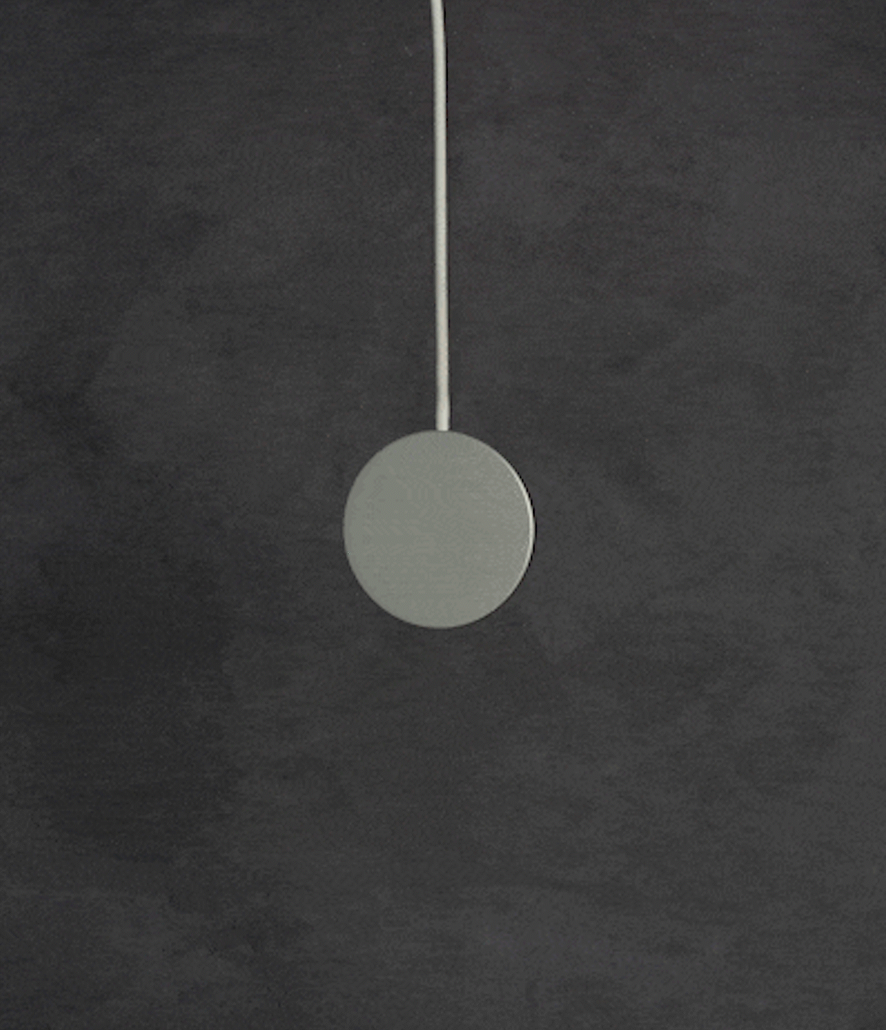 Galaxy S25 Ultra Case | Alles - A circular magnetic wireless charger hanging against a dark, textured gray background.