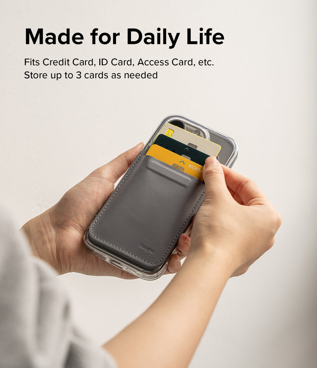 Card Holder | Stand Wallet Magnetic - Hands holding a phone case with a grey magnetic wallet storing three cards.