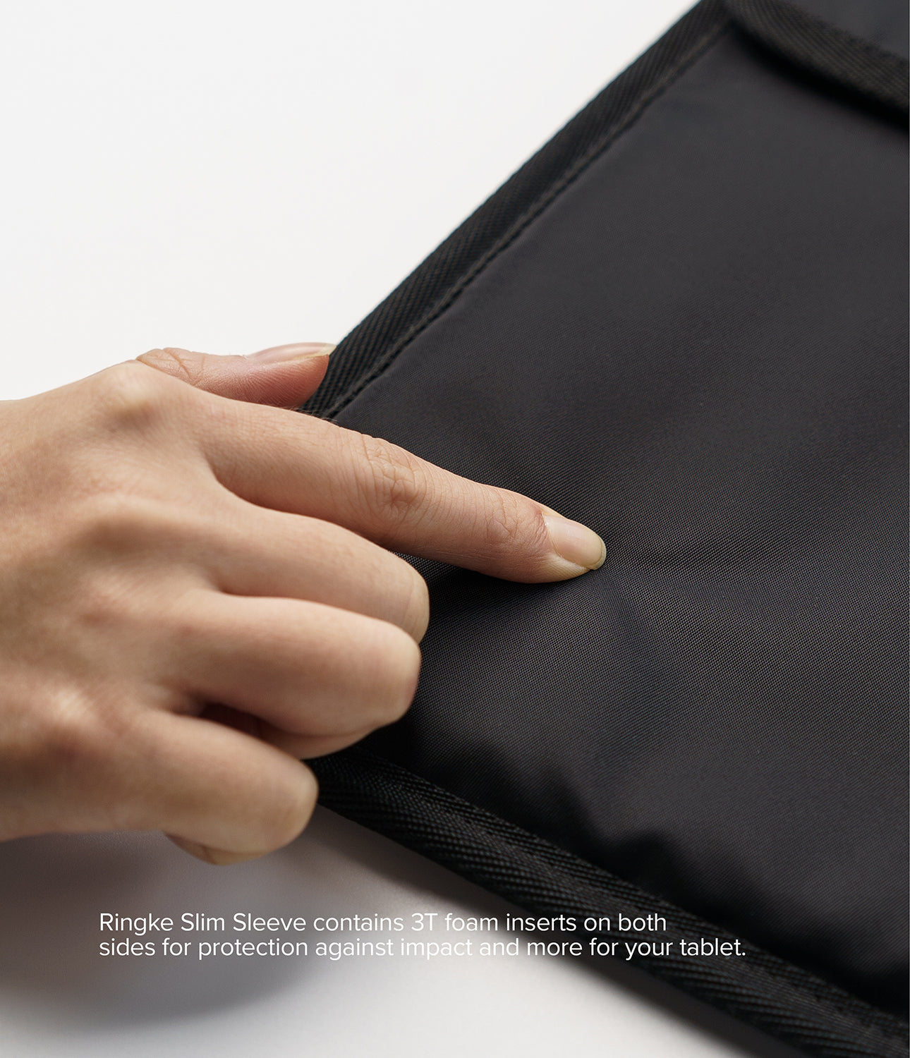 Pad Pouch | Slim Sleeve - A finger presses into the soft, padded black fabric of a protective tablet sleeve.