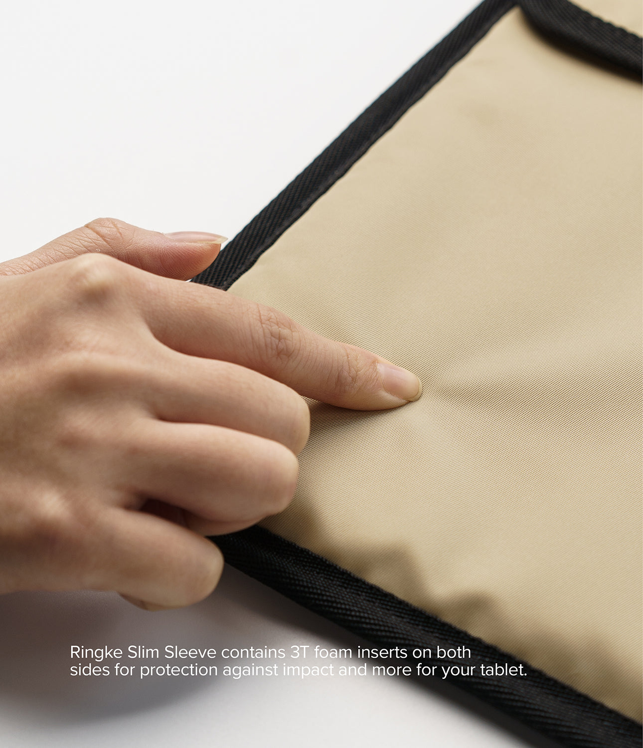 Pad Pouch | Slim Sleeve - A hand presses into the soft, beige fabric of a protective tablet sleeve with black trim.