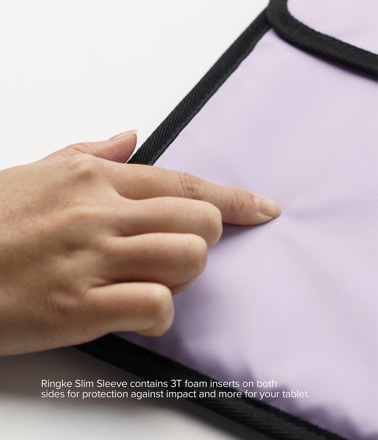 Pad Pouch | Slim Sleeve - A hand presses into the soft, light purple fabric of a protective tablet sleeve with black trim.