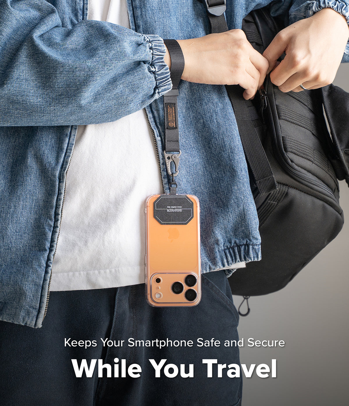 Holder Link Tactical Webbing Hand Strap - A person wearing a denim jacket uses a black tactical strap to secure a phone.