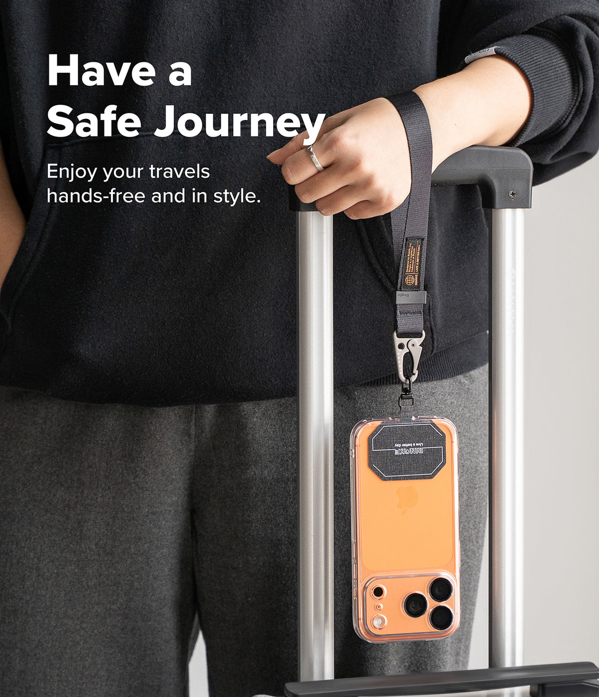 Holder Link Tactical Webbing Hand Strap - A black tactical wrist strap attached to a phone case hanging from a suitcase handle.