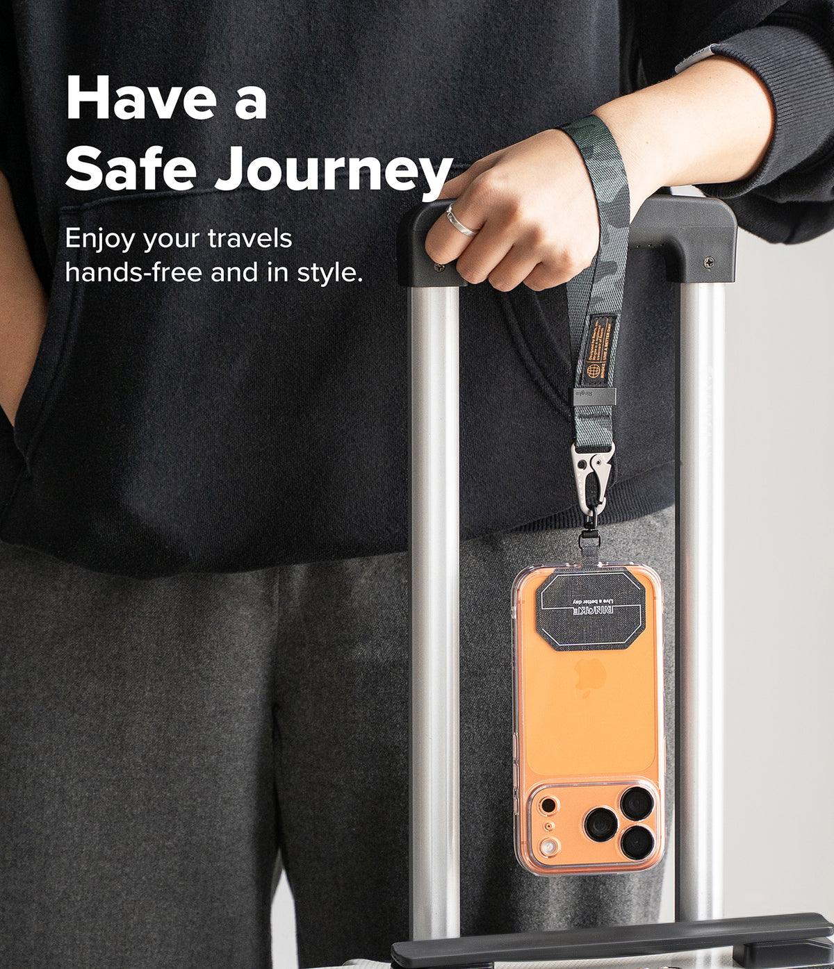 Holder Link Tactical Webbing Hand Strap - Camo wrist strap attached to a phone case hanging from a luggage handle.