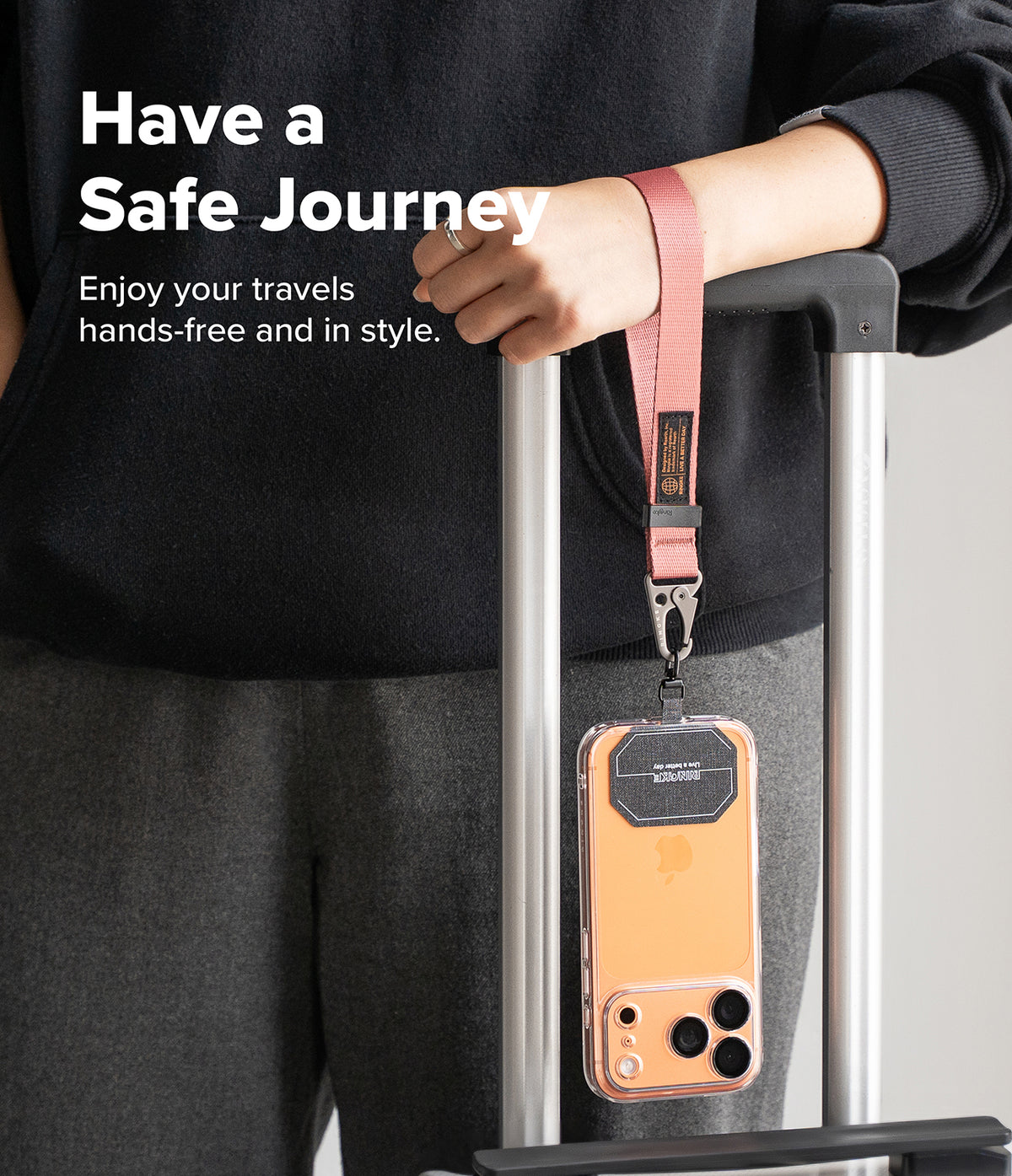 Holder Link Tactical Webbing Hand Strap - A pink tactical wrist strap attached to a smartphone hanging from luggage.