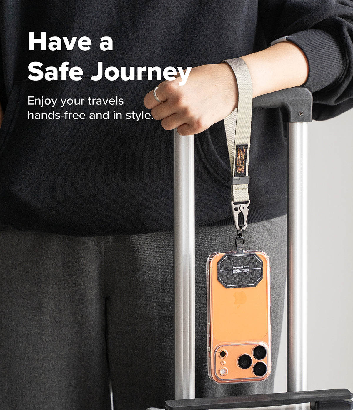 Holder Link Tactical Webbing Hand Strap - A beige tactical wrist strap attached to a phone case hanging from a suitcase.
