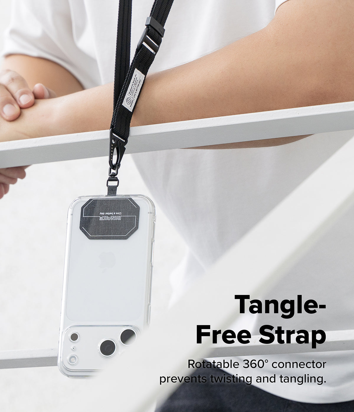 Holder Link Tactical Webbing Lanyard Strap - A clear phone case with a black lanyard strap hanging over a person's arm, with text reading 'Tangle-Free Strap' and a smaller descriptive subtitle. The person is wearing a white shirt, and the background is a clean white indoor setting.