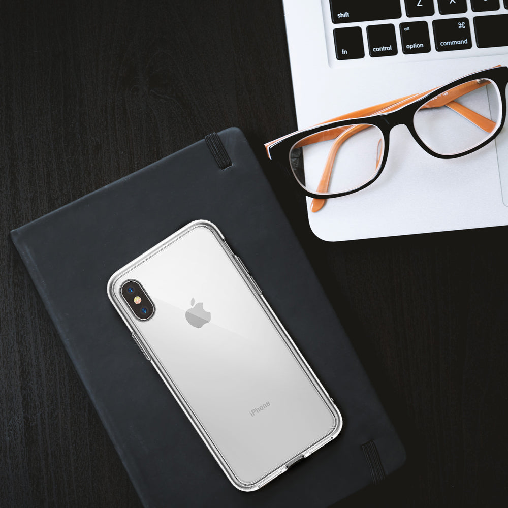 iPhone X Case | Fusion - Clear iPhone X case on a black notebook next to a laptop and orange-rimmed glasses.