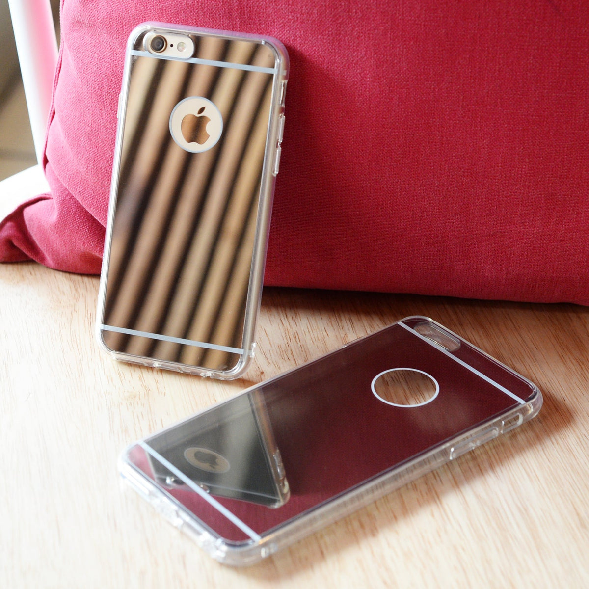 iPhone 6s / 6 Case | Mirror - Two reflective mirror-finish phone cases on a wooden surface against a red cushion.
