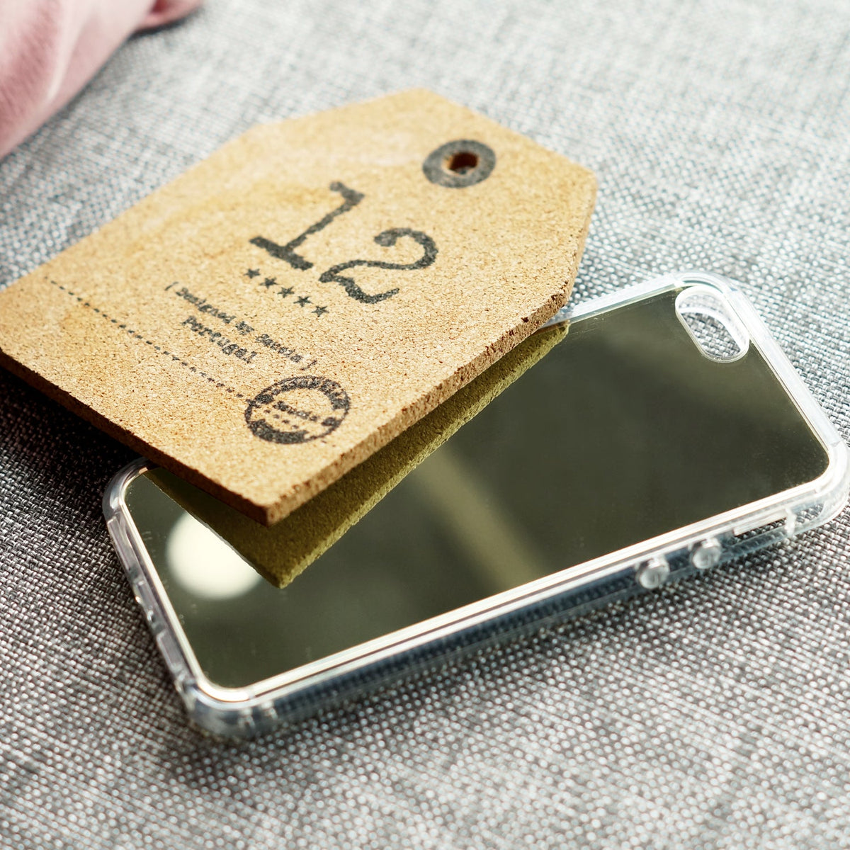 iPhone SE / 5s / 5 Case | Mirror - A reflective mirror phone case partially covered by a cork tag labeled 12 on a grey fabric.