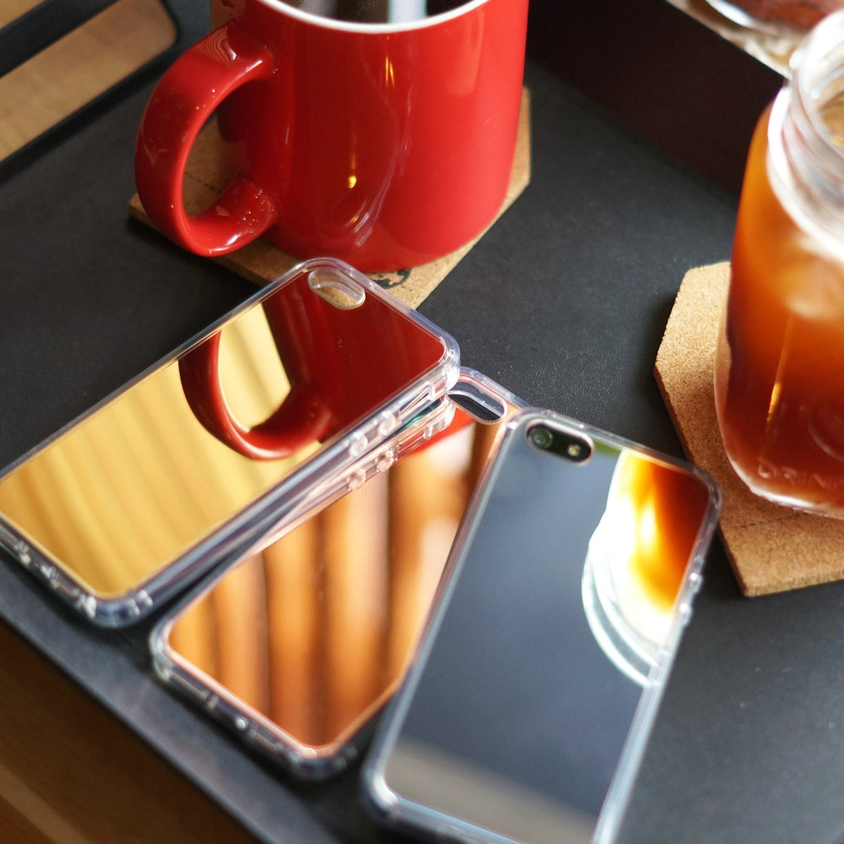 iPhone SE / 5s / 5 Case | Mirror - Two reflective mirror phone cases on a black tray next to a red mug and iced coffee.