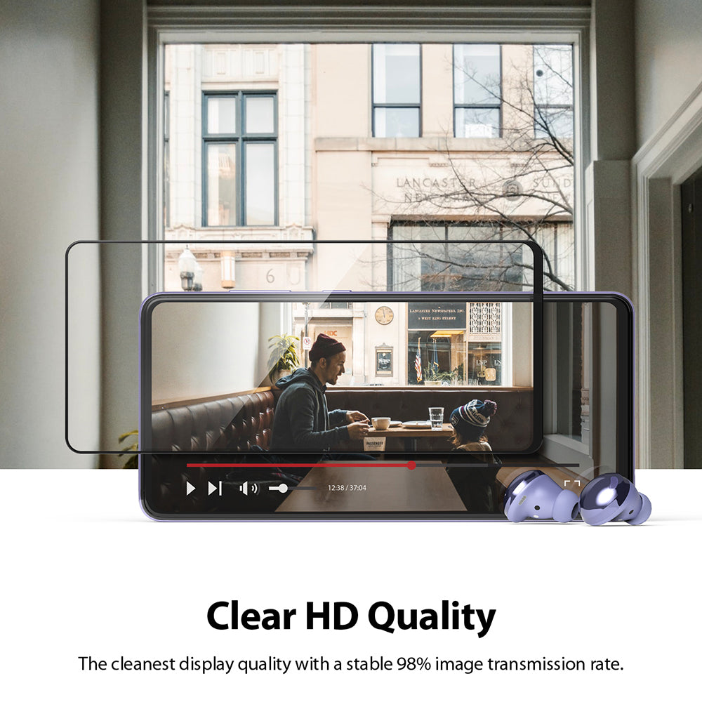 Galaxy A72 Screen Protector | Invisible Defender - Galaxy A72 Screen Protector - A clear screen protector hovering over a smartphone displaying a video, with purple earbuds.
