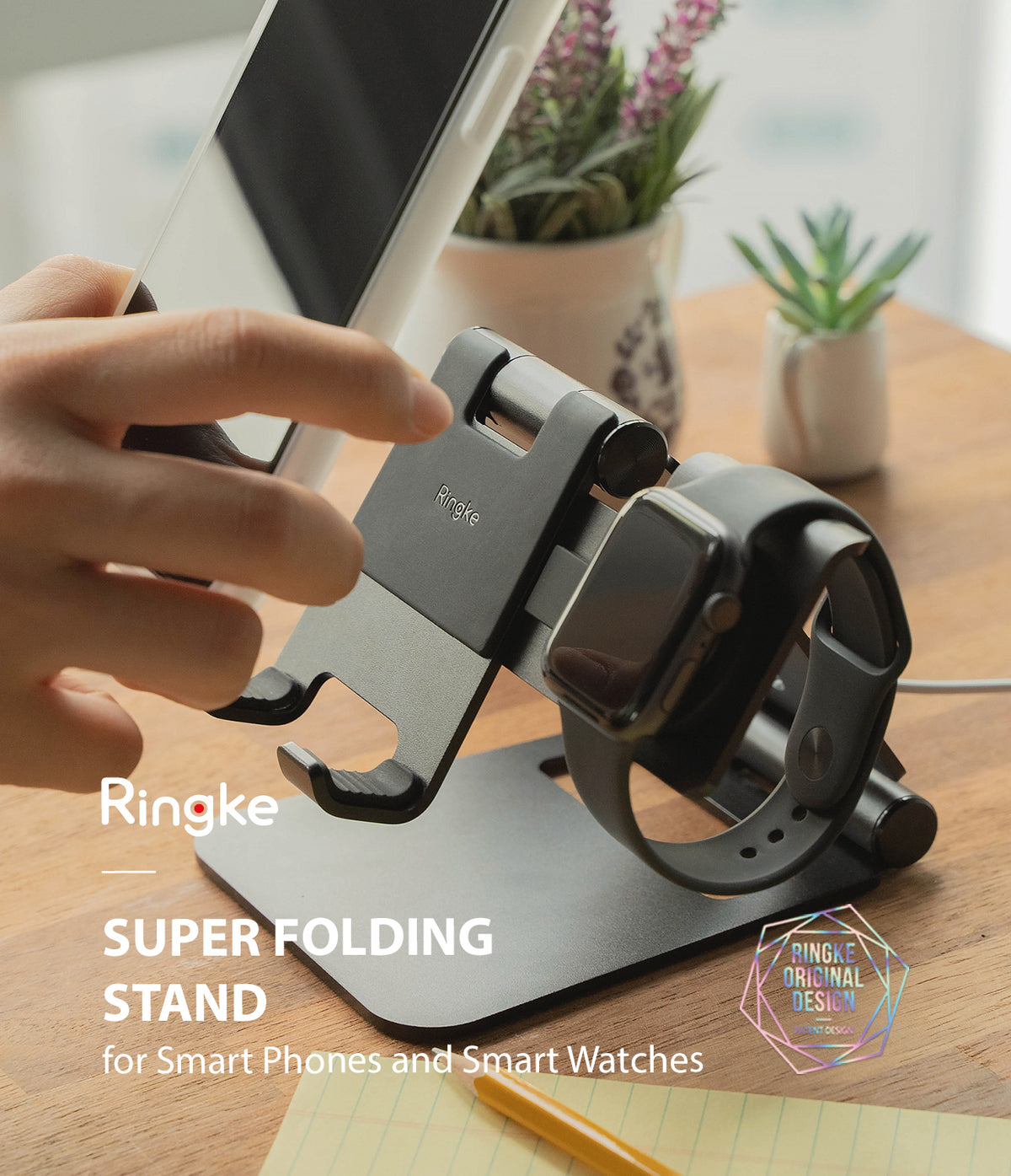 Super Folding Stand for Apple Watch - A black folding stand holding a smartphone and an Apple Watch on a wooden desk.