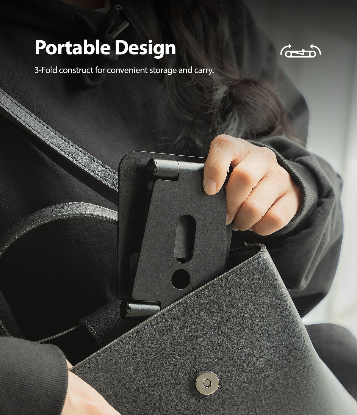 Super Folding Stand for Apple Watch - A person placing a compact, folded black metal stand into a leather handbag.