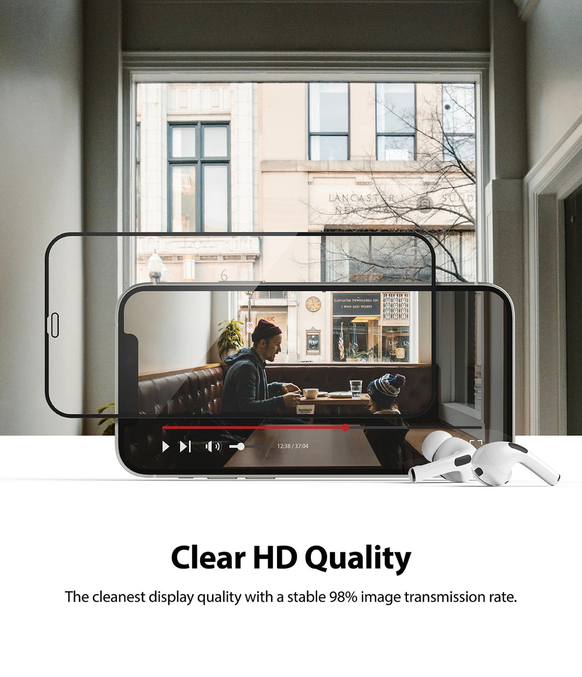iPhone 12 Mini Screen Protector | Invisible Defender Glass - iPhone 12 Mini Screen Protector - Clear glass overlaying a smartphone playing a video with white earbuds on a table.