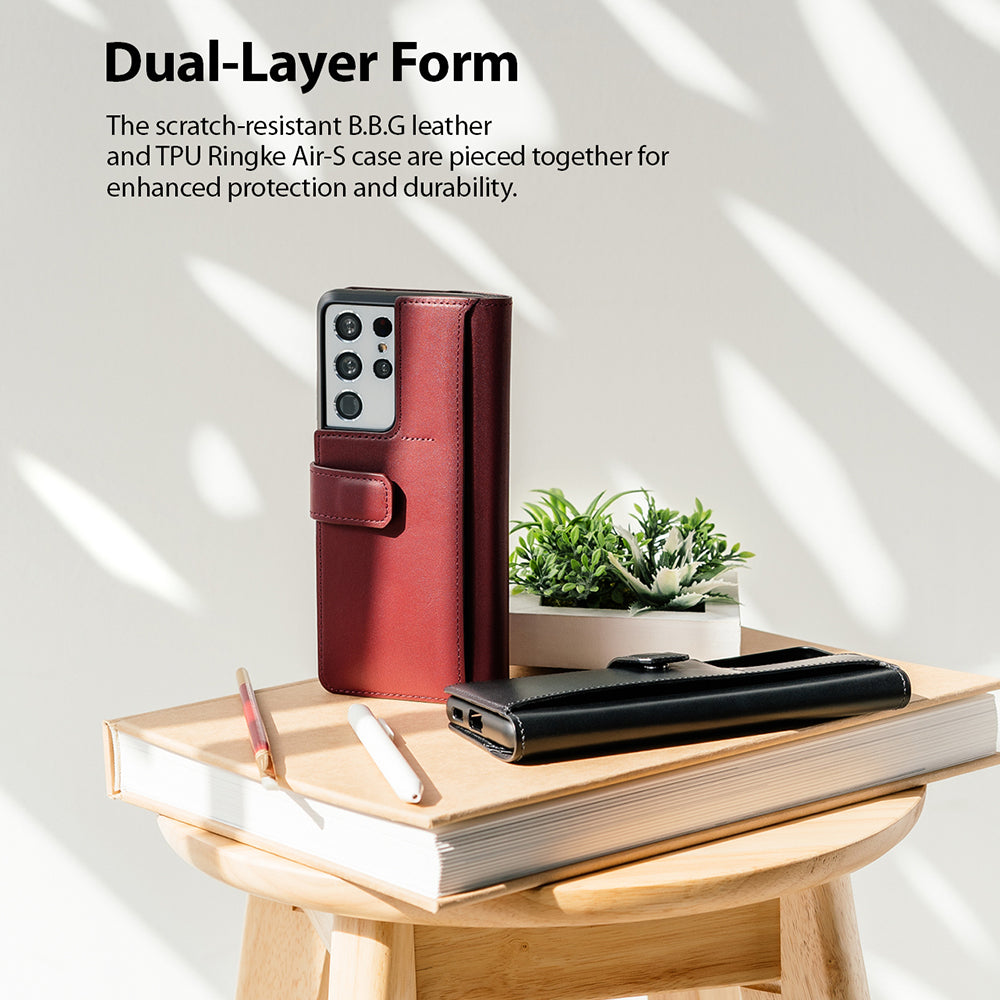 Galaxy S21 Ultra Case | Folio Signature+ - Maroon and black leather folio cases on a book atop a wooden stool.