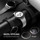 Galaxy Watch 4 Classic 42mm | Bezel Styling - Silver and black watch bezels displayed on a black stand with a watch.