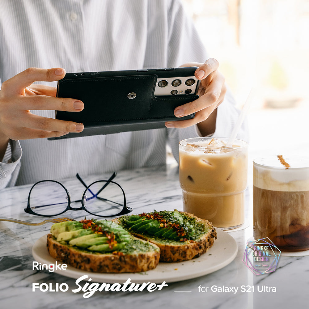 Galaxy S21 Ultra Case | Folio Signature+ - Person holding a black leather folio phone case over avocado toast and coffee.