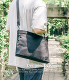 2-Way Bag - A person wearing a black crossbody bag with a textured strap over a light-colored t-shirt in a park setting.