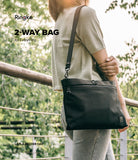 2-Way Bag - A person wearing a black crossbody bag with a zippered top and adjustable strap outdoors.