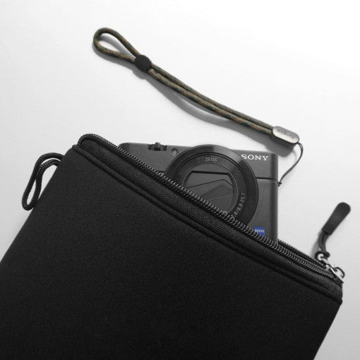 Cushion Pouch - A black zippered camera pouch holding a Sony compact camera with a wrist strap against a white background.