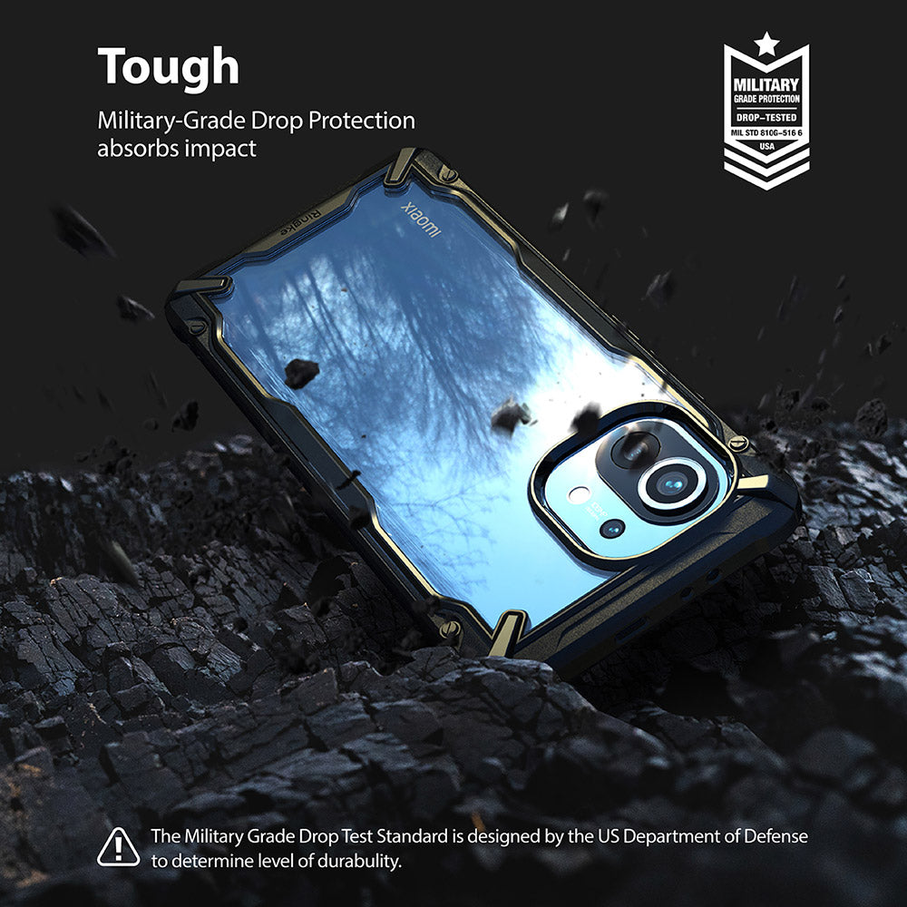 Mi 11 Case | Fusion-X - A rugged black and clear phone case resting on dark, textured rock with debris flying around it.