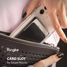 Card Holder | Slot [Solid - 2 Cards] [1 Pack] - A hand slides a smartphone with a black adhesive card holder into a purse.