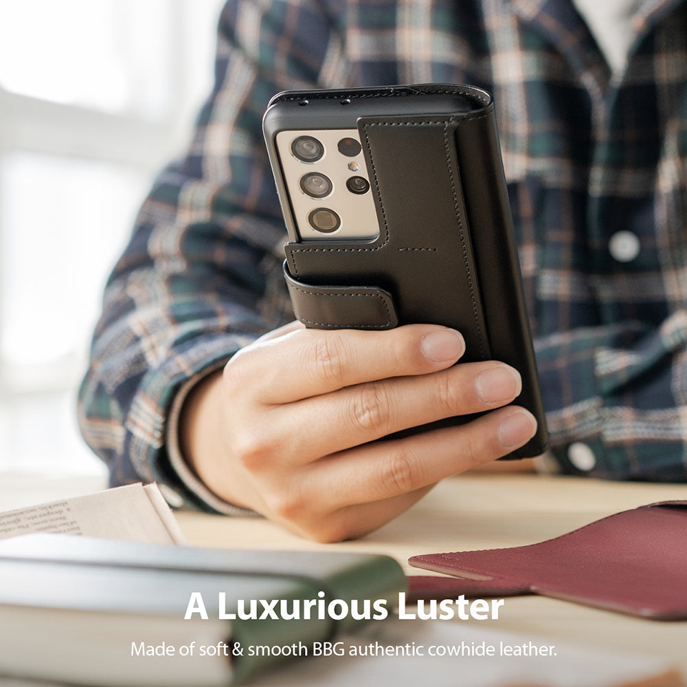 Galaxy S21 Ultra Case | Folio Signature+ - Hand holding a black leather folio case on a Galaxy S21 Ultra smartphone.