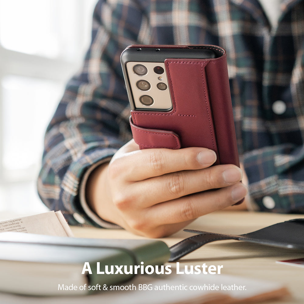 Galaxy S21 Ultra Case | Folio Signature+ - A hand holds a burgundy leather folio case on a Galaxy S21 Ultra phone.