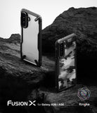 Galaxy A36 / A56 Case | Fusion-X - Two Fusion-X phone cases on dark rocks, one clear and one with a black camo pattern.