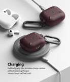 AirPods 3 Case | Onyx - Two dark maroon AirPods 3 cases with carabiners charging on a wireless pad with visible green lights.