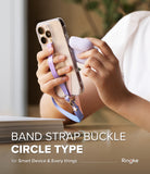 Band Buckle Circle Type Strap - Hands holding a phone with a purple fabric wrist strap featuring a metal ring and star charms.