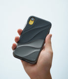 iPhone XR Case | Wave - A hand holds a black phone case with a textured, wavy design and a yellow camera cutout.