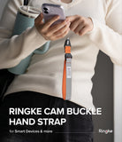 Cam Buckle Hand Strap - Person holding a phone with a Ringke cam buckle hand strap, wearing a white sweater and black pants.