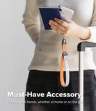 Cam Buckle Hand Strap - Person holding a phone with a lanyard, wearing a beige sweater and black pants, on a light gray background.