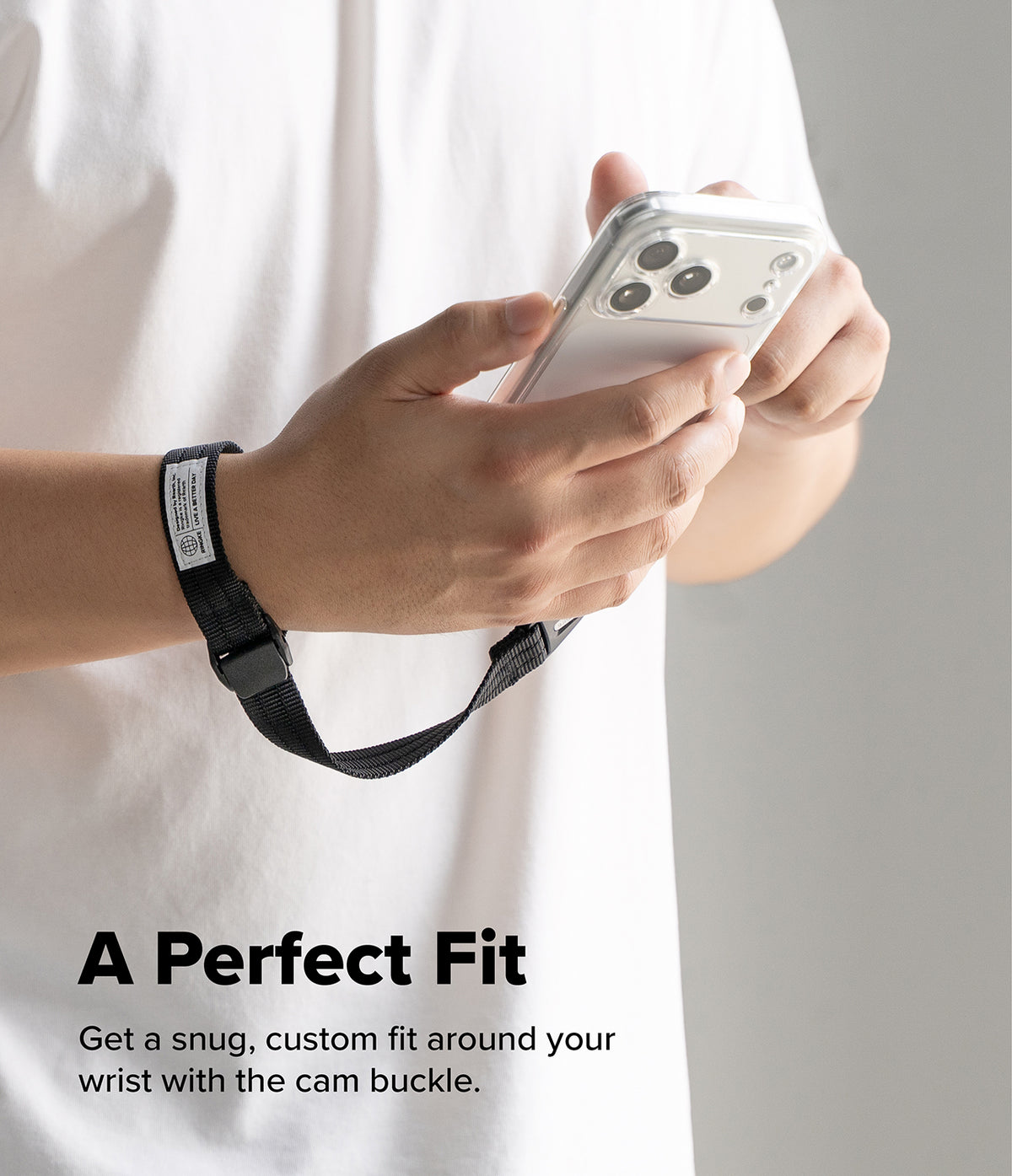 Cam Buckle Hand Strap - A person in a white shirt holding a smartphone while wearing a black adjustable wrist strap with a cam buckle. Text at the bottom reads, 'A Perfect Fit Get a snug, custom fit around your wrist with the cam buckle.
