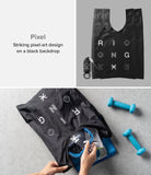 Day-Me Bag - Black tote with pixel-art graphics, shown folded with a keychain and being packed with gym gear.