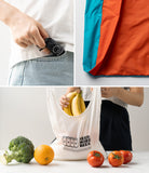 Day-Me Bag - A foldable, colorful tote bag shown packed in a small pouch, unfolded, and filled with groceries.