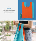 Day-Me Bag - Orange and blue reusable tote bag shown folded with a carabiner and being carried by a person.