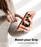 Dual Magnetic Smart Ring - A person holding a smartphone with a black magnetic ring attached to the back for a secure grip.