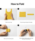 Day-Me Bag - Four-step instructional guide showing how to fold and roll a yellow smiley-face tote bag into a small pouch.