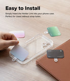Holder Link Eyelet Keyring - Hand inserting a colorful, flat strap anchor into a clear phone case on a wooden surface.