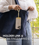 Holder Link Flow Finger Ring - A person holding a phone attached to a cream-colored finger strap hanging from a blue tote bag.