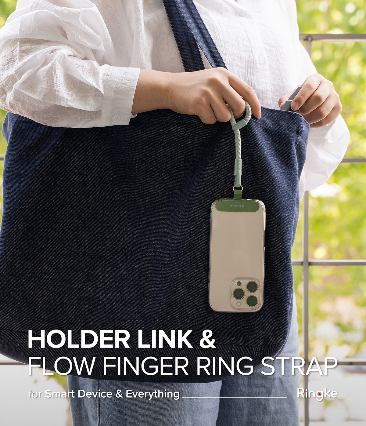 Holder Link Flow Finger Ring - A person holding a phone attached to a green finger ring strap hanging from a denim tote bag.
