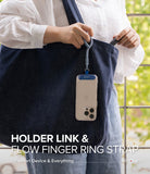 Holder Link Flow Finger Ring - A person holding a blue finger ring strap attached to a smartphone hanging from a denim tote bag.