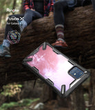 Galaxy A71 Case | Fusion-X - Black rugged phone case with clear back floating against a blurred outdoor forest background.
